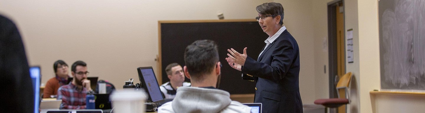 A middle aged woman lecturing in a classroom full of adults