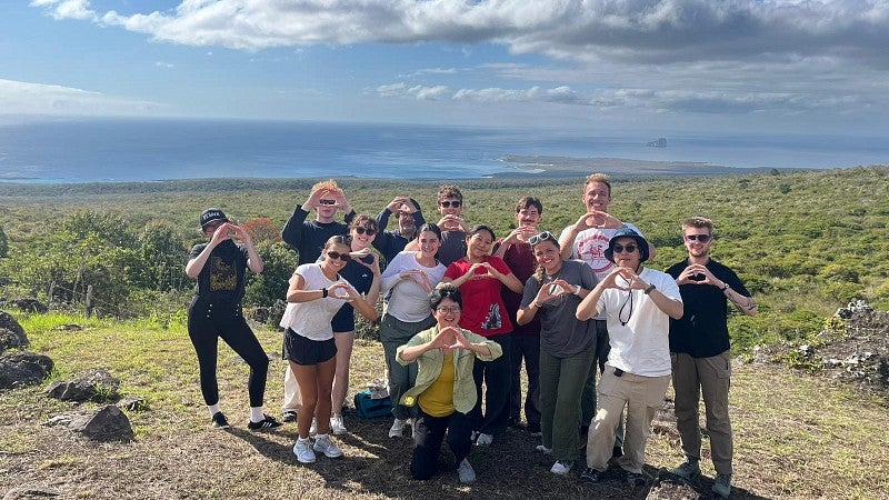 Group of students in Galapagos throwing their Oregon "O"