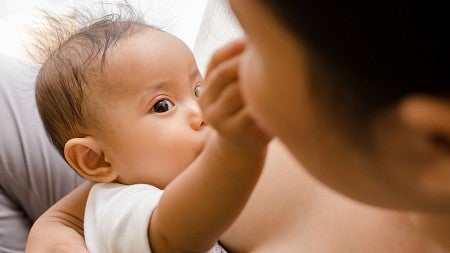 Mother breastfeeding her newborn baby beside window