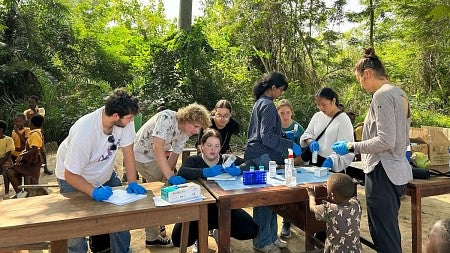 A group of university students at a long table preparing medical supplies for a community in Ghana